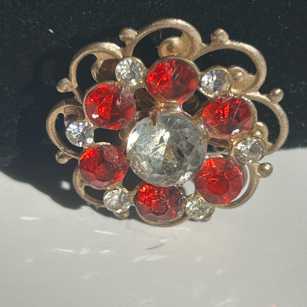 Gold-tone openwork vintage brooch with vivid red and clear rhinestones